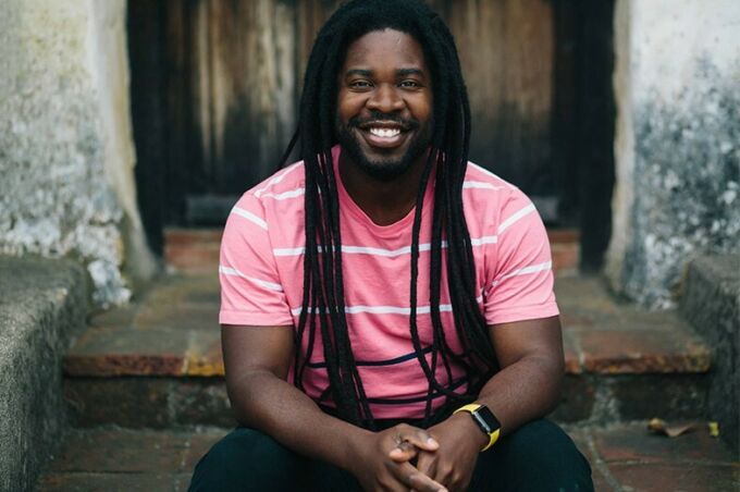 A man with long dreadlocks smiles.