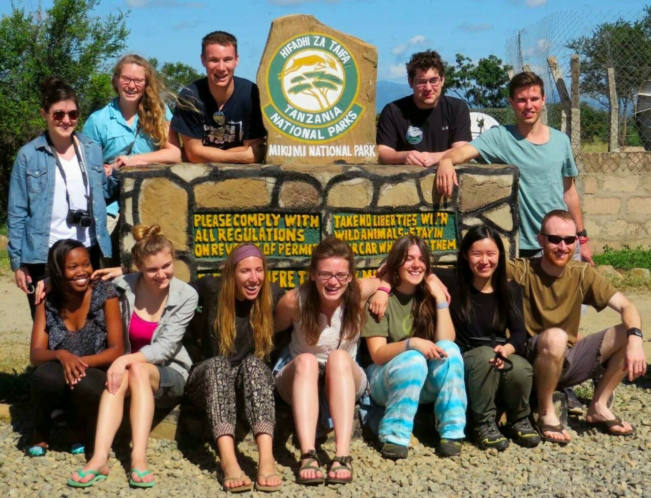 Penn State landscape architecture students grouped around a Mikumi National Park sign in Tanzania