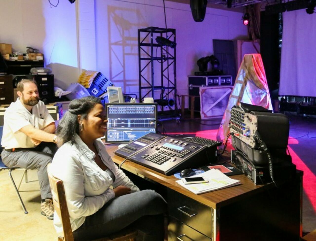 Theatre student sitting behinds a technical control board in the Penn State TAPS facility.