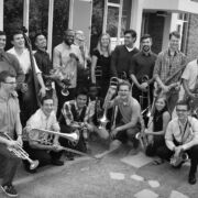 Black and white group photo of Marko Marcinko and his students smiling and holding instruments.