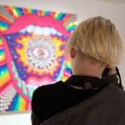 A student photographing colorful artwork on display in Zoller Gallery.