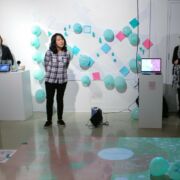 First year M.F.A. student exhibition with an interactive floor projection and teal balloons.