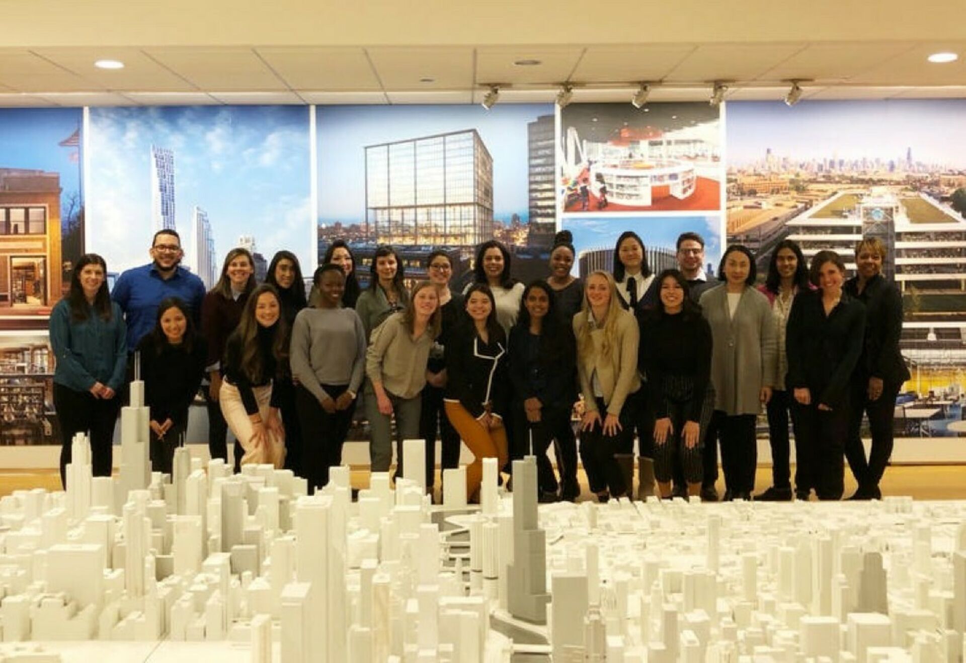 A group of Penn State Master of Architecture students gathered behind an elaborate cityscape model in the offices of architectural firm SOM.