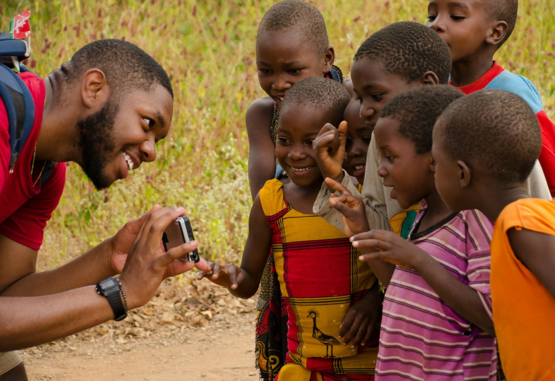 Close-up of Penn State Landscape Architecture student showing a camera to a group of smiling Tanzanian children