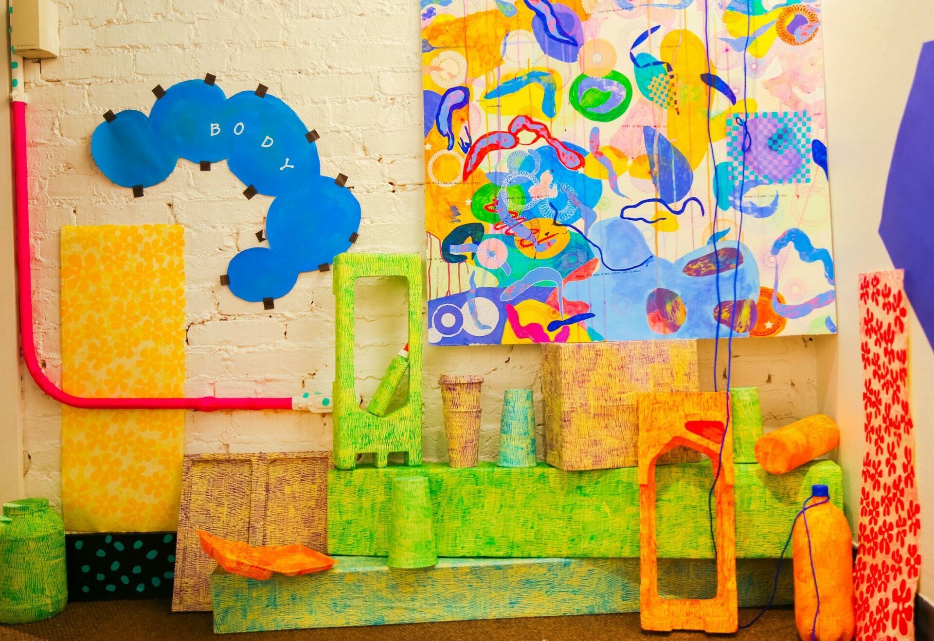 Brightly-colored textured floor objects and wall art displayed as part of an exhibit in Patterson Gallery located on Penn State University Park campus.