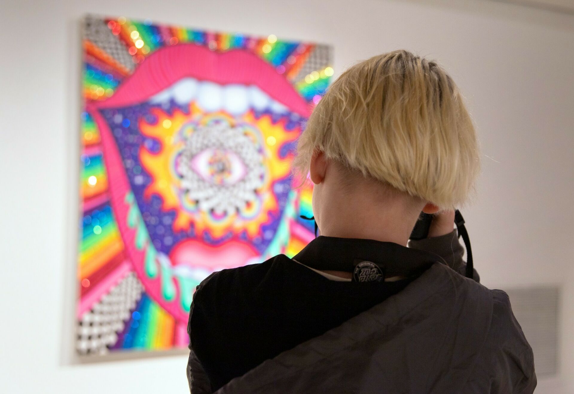 A student photographing colorful artwork on display in Zoller Gallery.