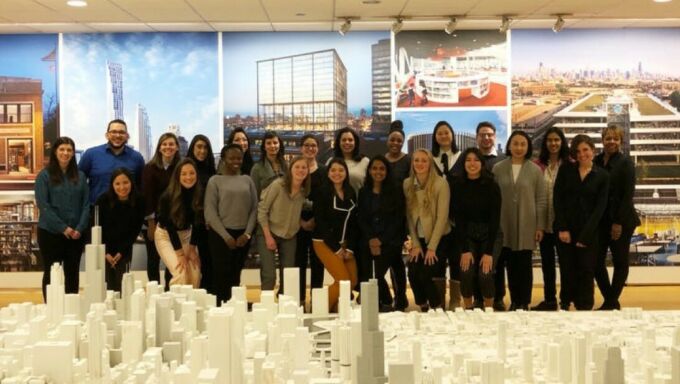 A group of Penn State Master of Architecture students gathered behind an elaborate cityscape model in the offices of architectural firm SOM.