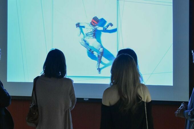A view of the backs of two women who are viewing a projected image on a screen.