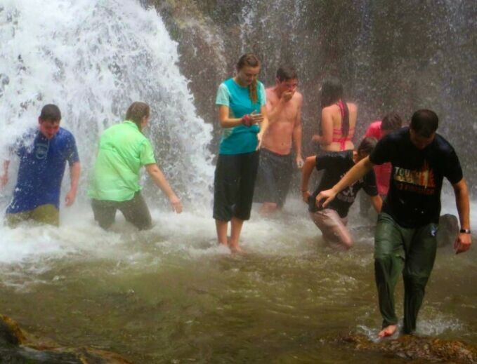 students wading in waterfall