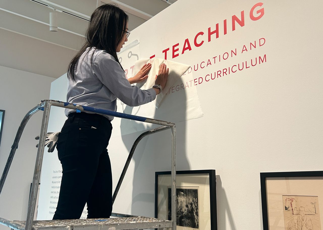 Woman on ladder putting letters on wall