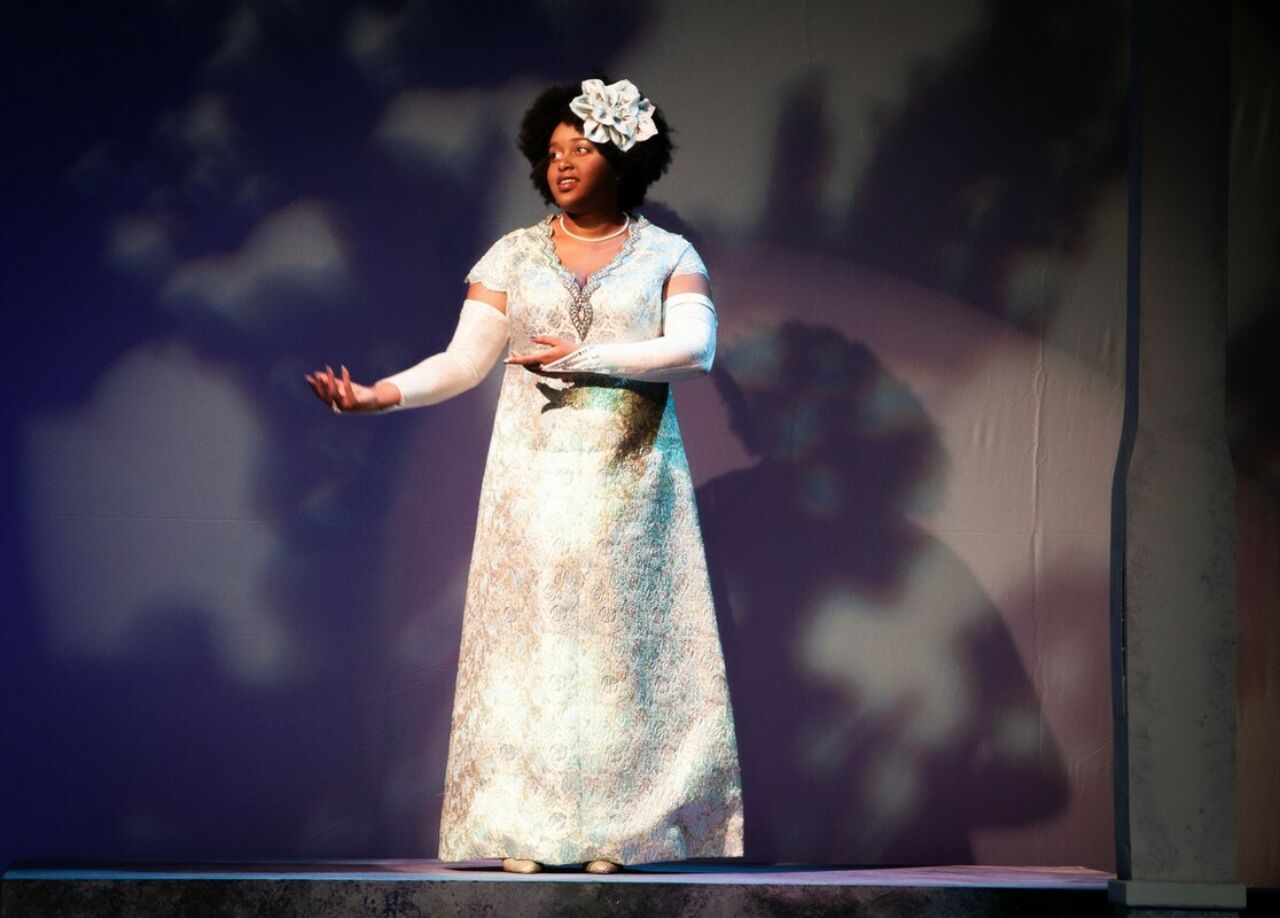 A Black actress in a gown performing on stage.