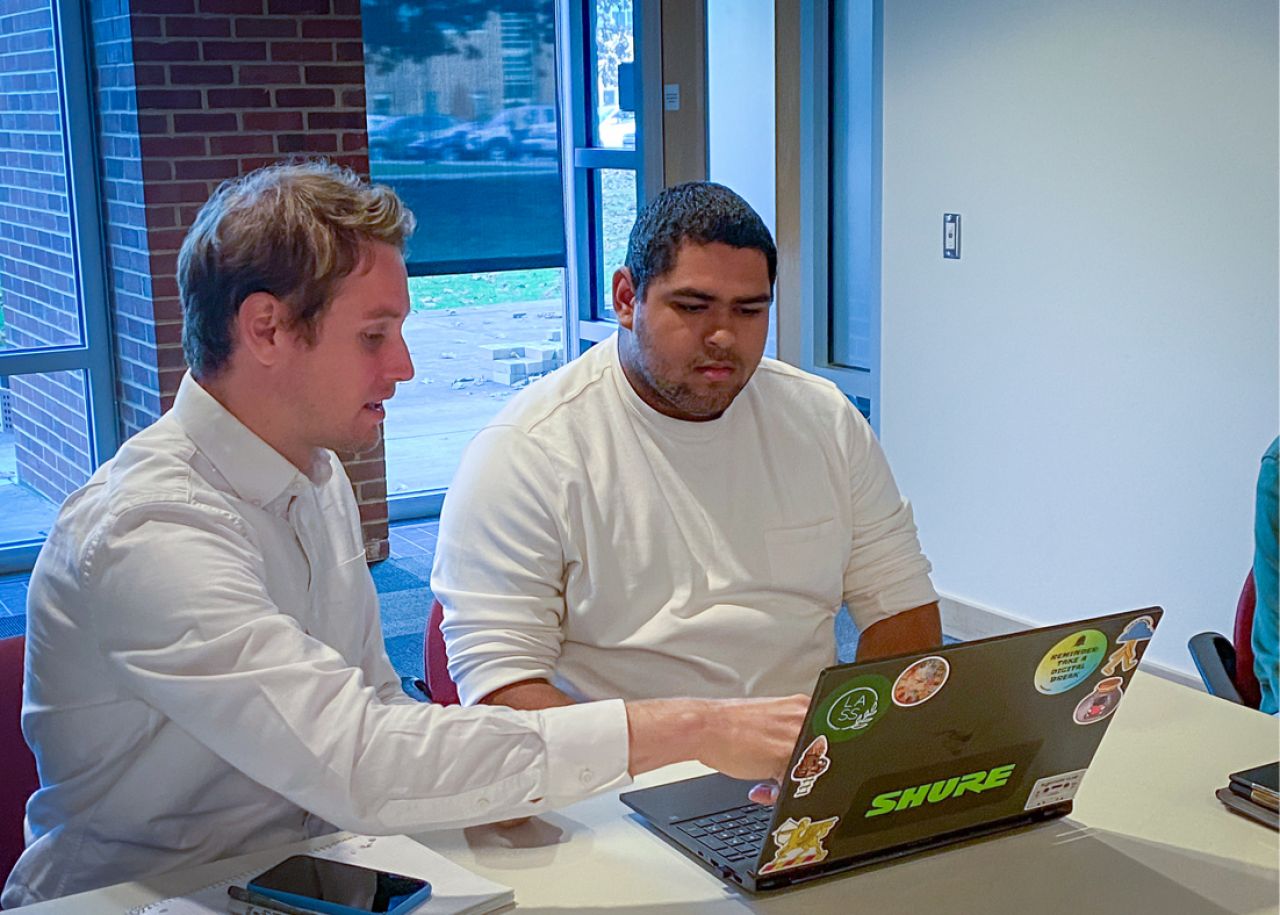 Alex McKeag, at left, points at a laptop in front of Misael Marin.