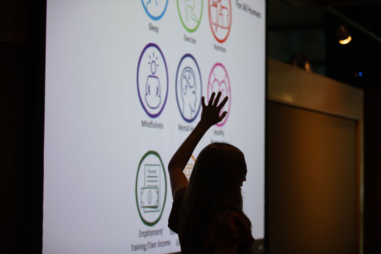 The silhouette of a woman giving a lecture on a display screen from her talk.