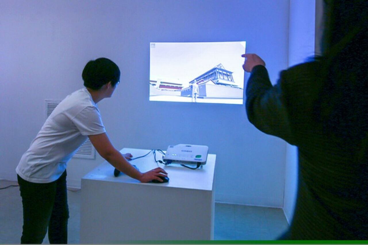 Student using digital projector to display visual presentation on the wall of a blue-light cast room.