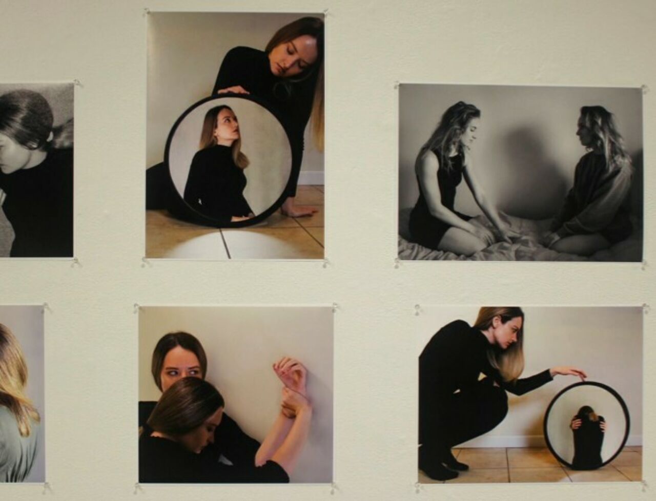 Six photographs of two females, the prints pinned to a cream-colored wall.