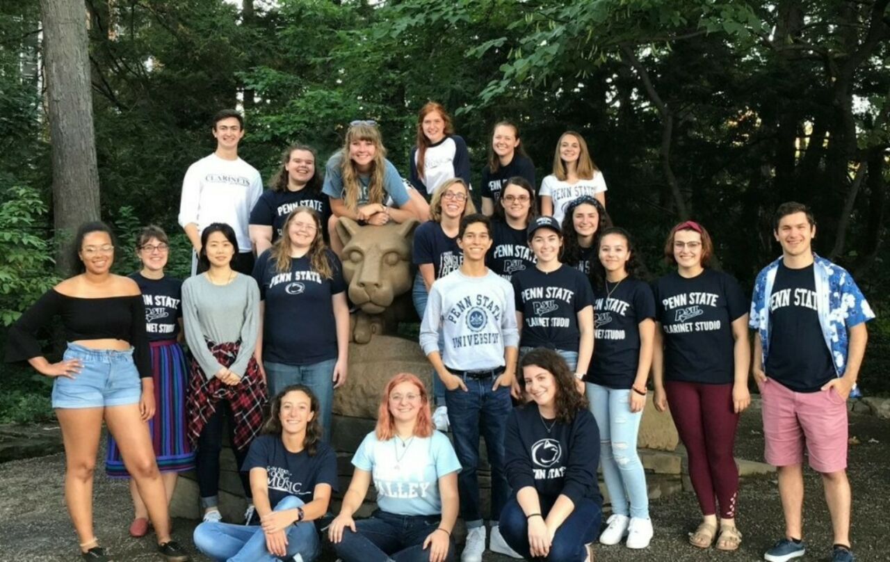 A group of Clarinet Studios's students are taking photo with Nittany Lion Statue