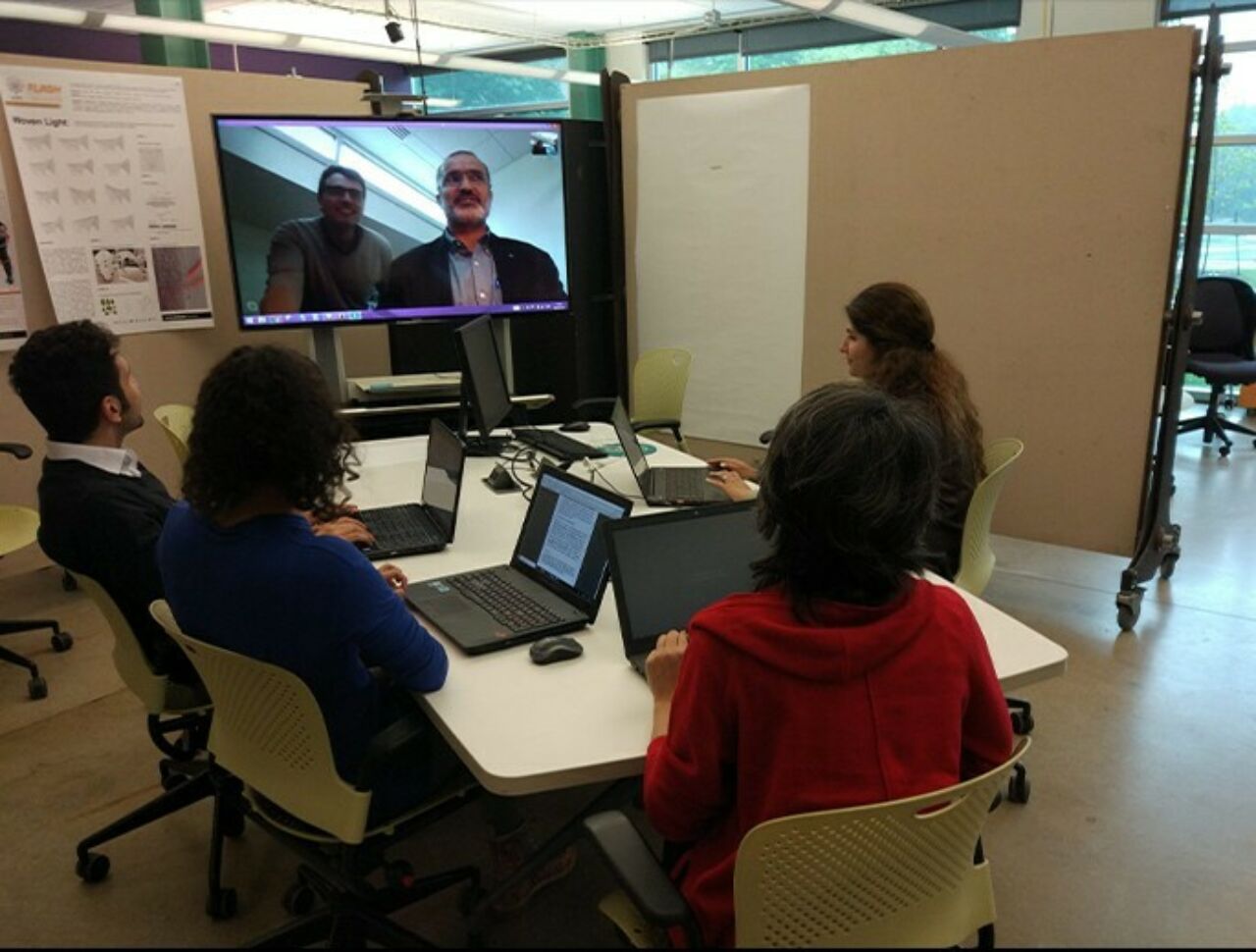 Students sitting around a conference table videoconferencing with a researcher.