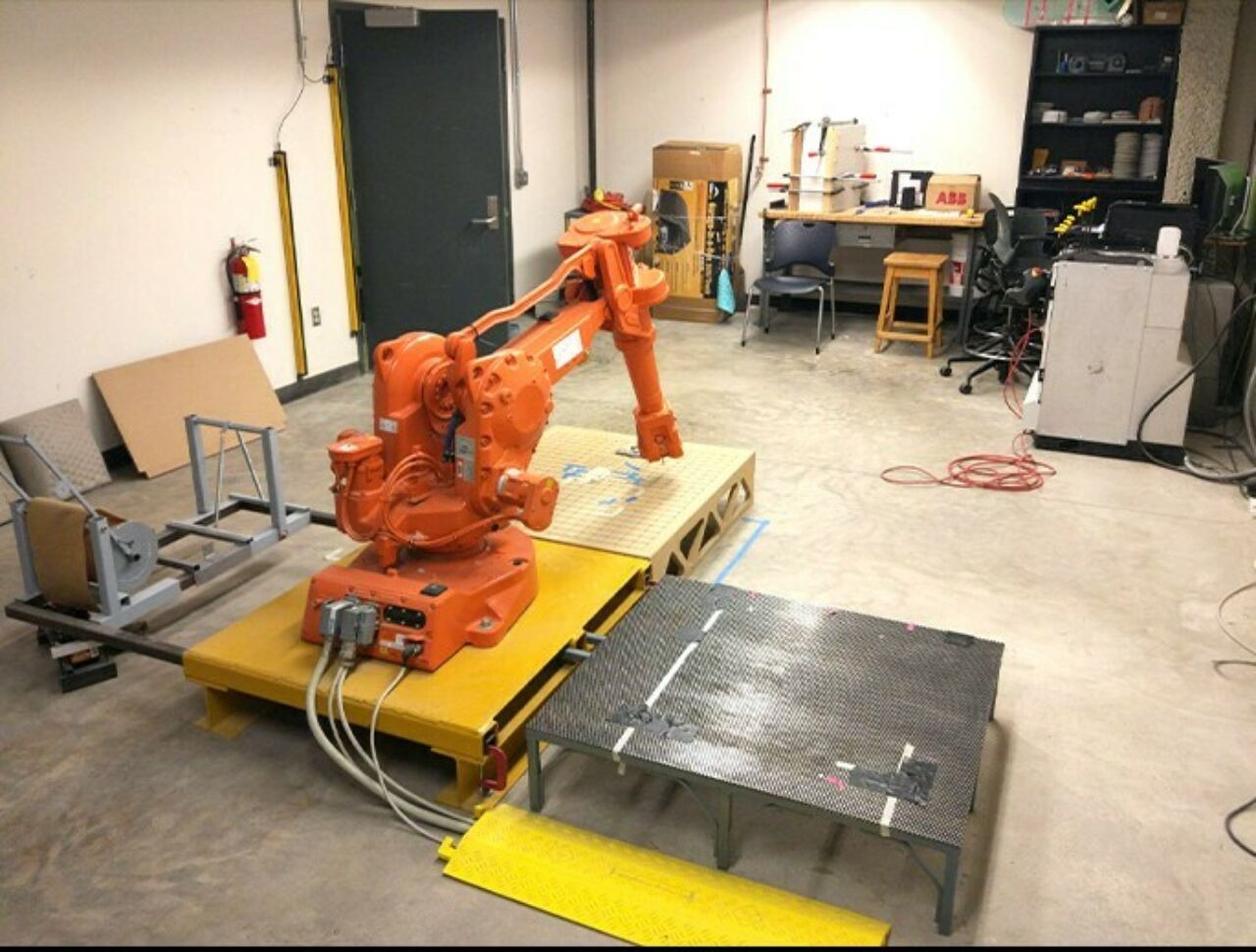 large orange robot with arm on platform in workspace