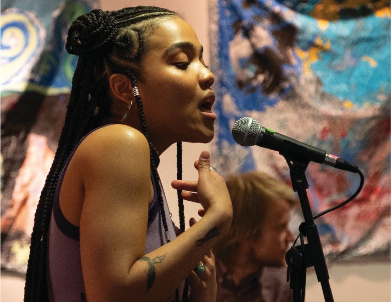 A young Black woman singing on stage.