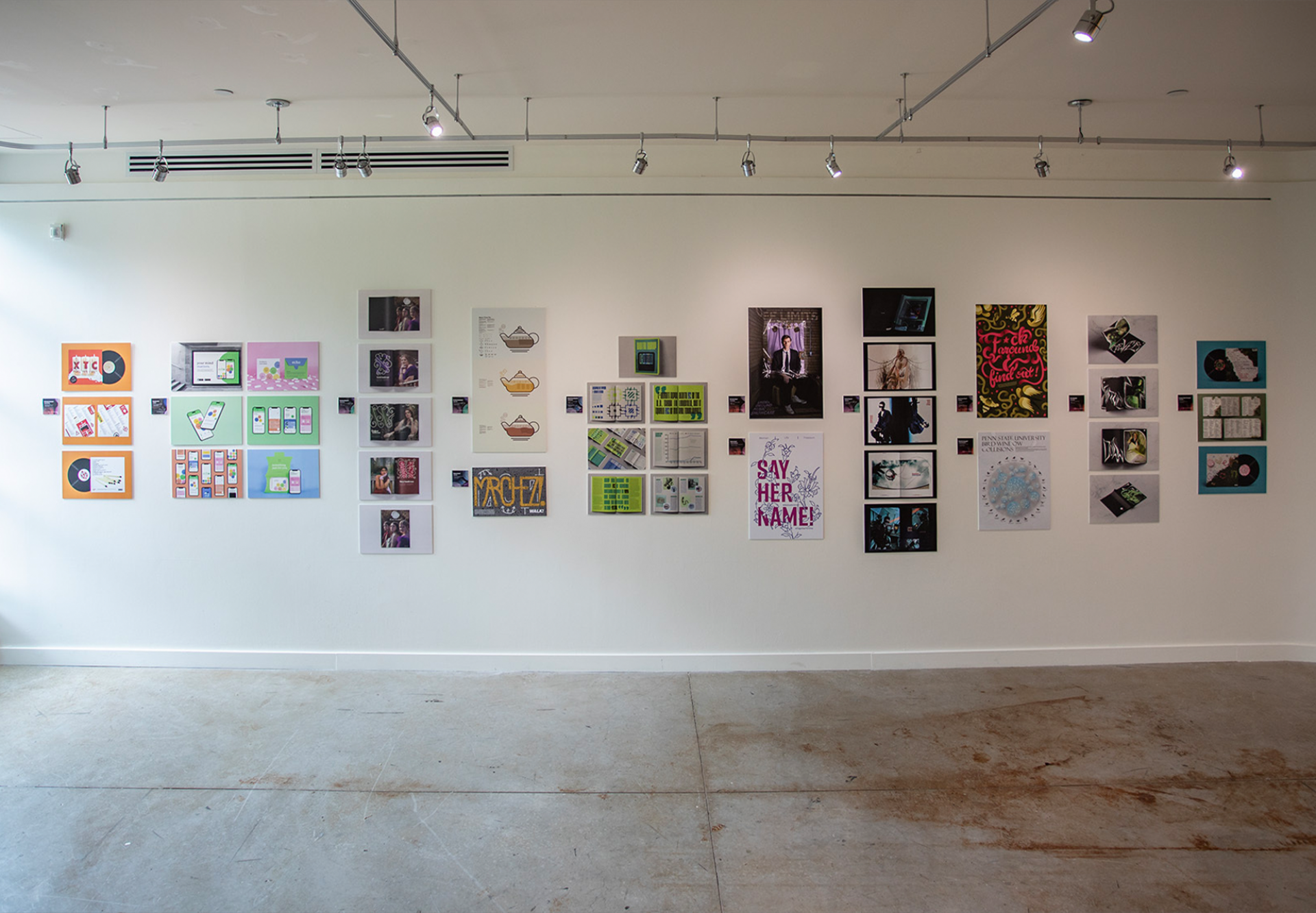 Graphic design student projects hung as part of an exhibition on a gallery wall.