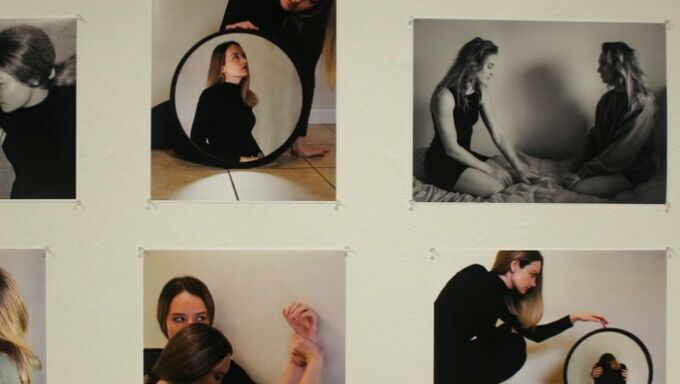 Six photographs of two females, the prints pinned to a cream-colored wall.