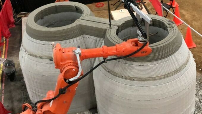 Orange multi-axis industrial CNC robots being used for 3d-printing concrete forms.