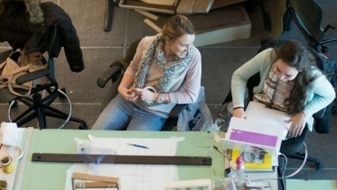 Photo shot from above of two students in front of a green drafting table.