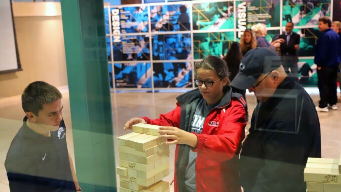 A prospective student and her father play Jenga in between sessions at Spend a Summer Day.