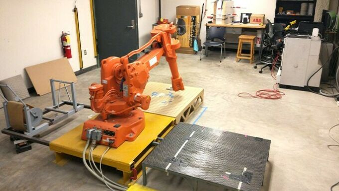 large orange robot with arm on platform in workspace