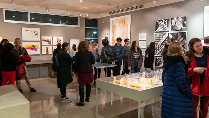 Students and faculty milling around an exhibition in the Rouse Gallery.