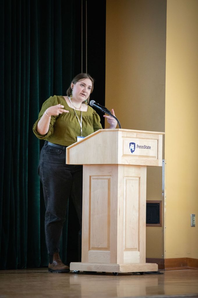 A woman stands at a podium with a microphone speaking