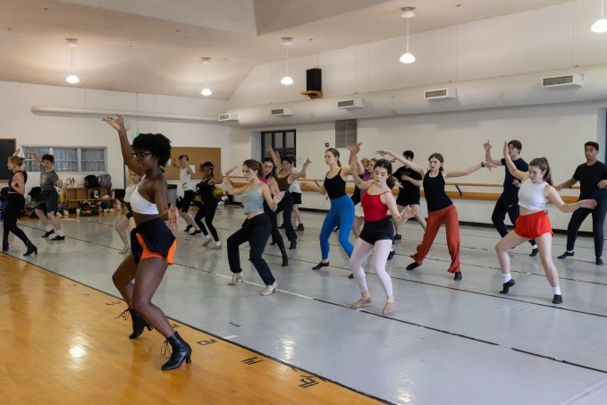 Group of theatre camp dancers in studio moving their bodies in freestyle facing a mirror.