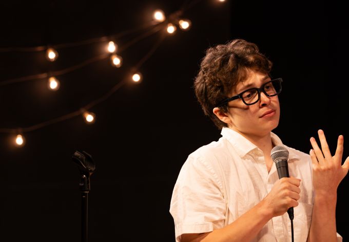 Individual male theatre student wearing glasses with an expression of sadness on his face.