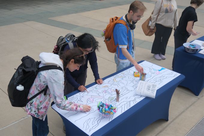 Students participating in a coloring activity at the Mending Walls Penn State mural unveiling