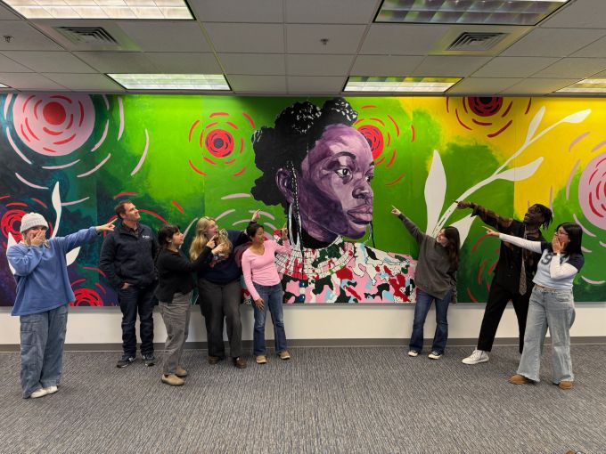 Members of the Mending Walls Penn State Committee point at the installed 2024 mural.