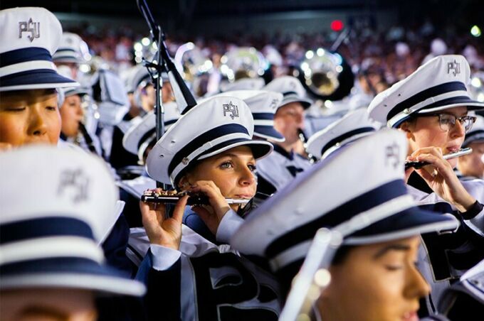 Blue band members play their flutes during a Penn State football night game.