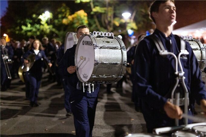 Blue band members march and play their drums during the Penn State homecoming parade.