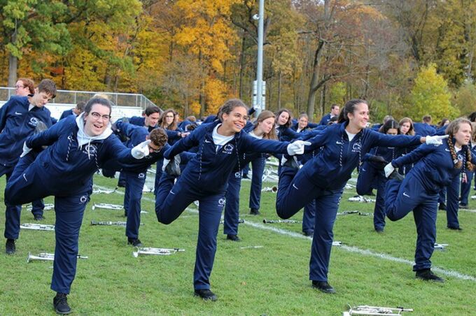 Laughing blue band trumpet players stretch their legs before marching in the homecoming parade.