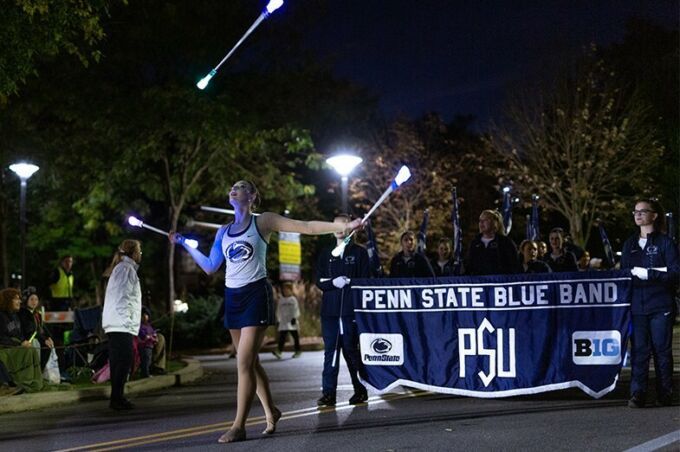 The feature twirler leads the blue band down college avenue as they perform during the Penn State homecoming parade.