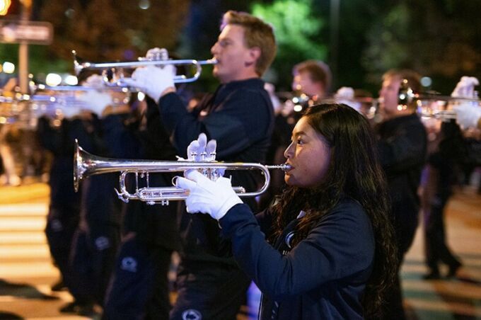 Blue band members march and play their trumpets during the Penn State homecoming parade.