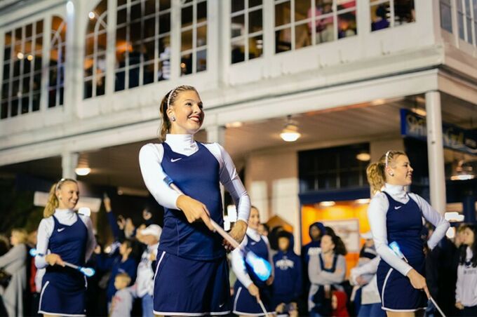 Blue band majorettes perform a routine with lit batons for spectators during the Penn State homecoming parade.