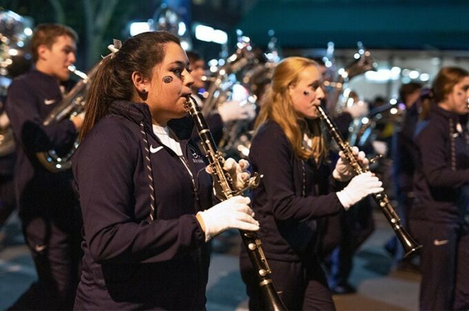 Blue band members march and play their clarinets during the Penn State homecoming parade.