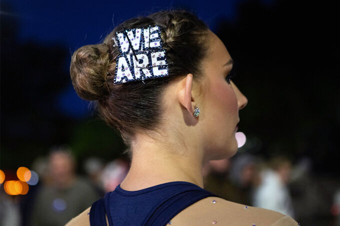 A majorette with an adorned "we are" pin in her hair, looks out into the crowd during the Penn State homecoming parade.
