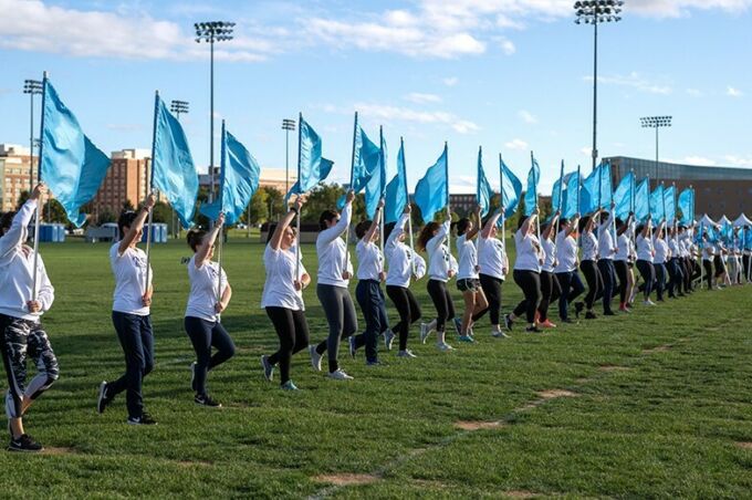 The blue band silks holding cyan flags march across the field in a perfect line during camp.