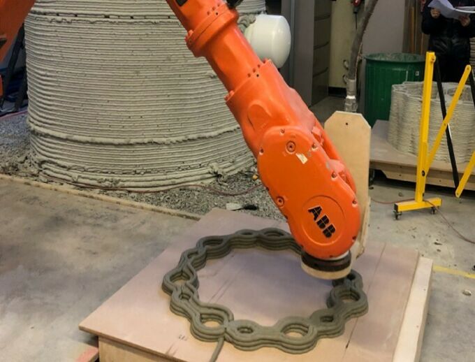 Orange arm of multi-axis industrial robot being used for 3d-printing concrete.