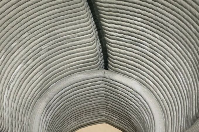 Interior close-up of 3d-printed hollow concrete form, showing stacked, offset layers of printed concrete.
