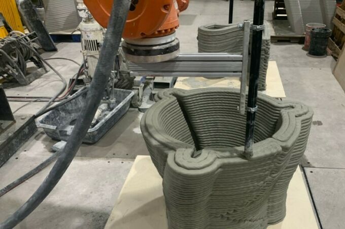 Overhead view of ABB industrial robot 3d-printing a large hollow concrete form.