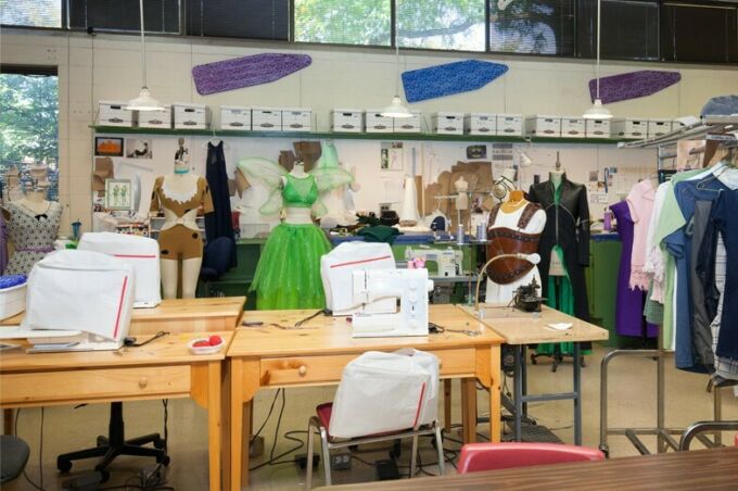 Costume shop showcasing numerous costumes and sewing machine stations.