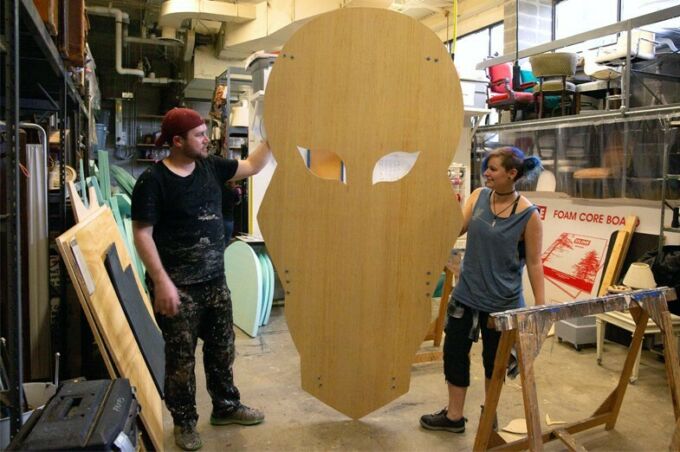 Scenic design students creating a face prop out of wood for a play.
