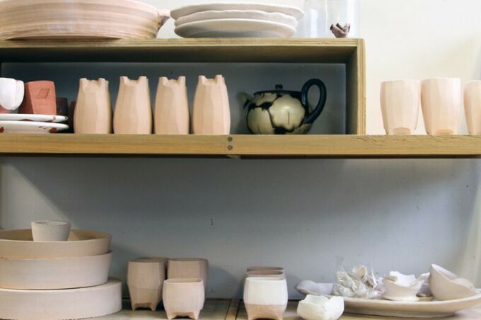 Various pottery objects displayed on wooden racks in the SoVA Ceramics Studio.